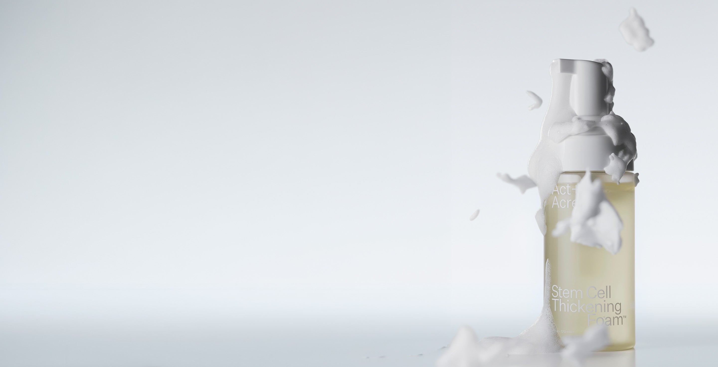A bottle of Stem Cell Thickening Foam with foam splashing around it, set against a light gray background.